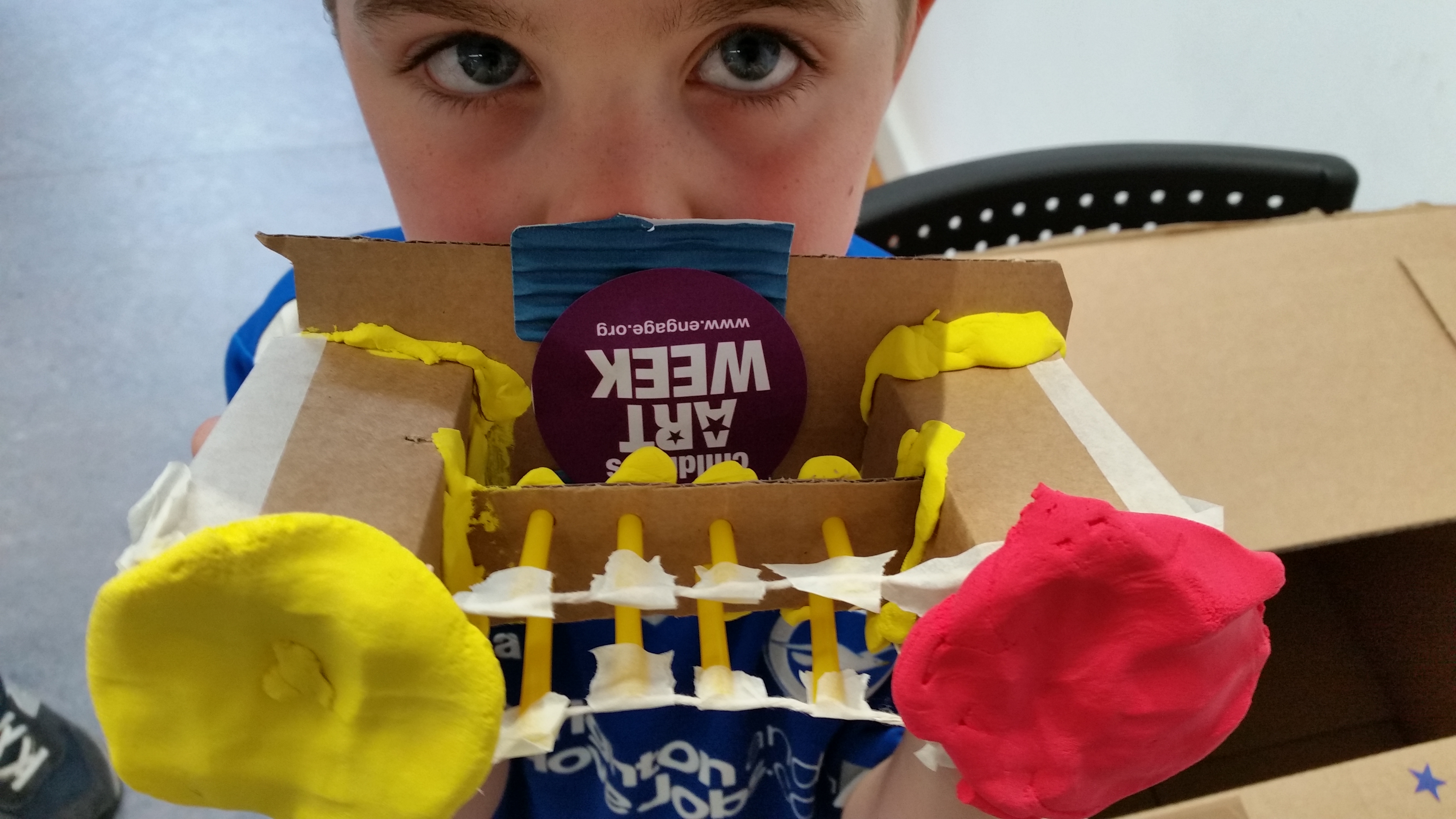 A boy peeps over his creation: a cardboard box bridge.
