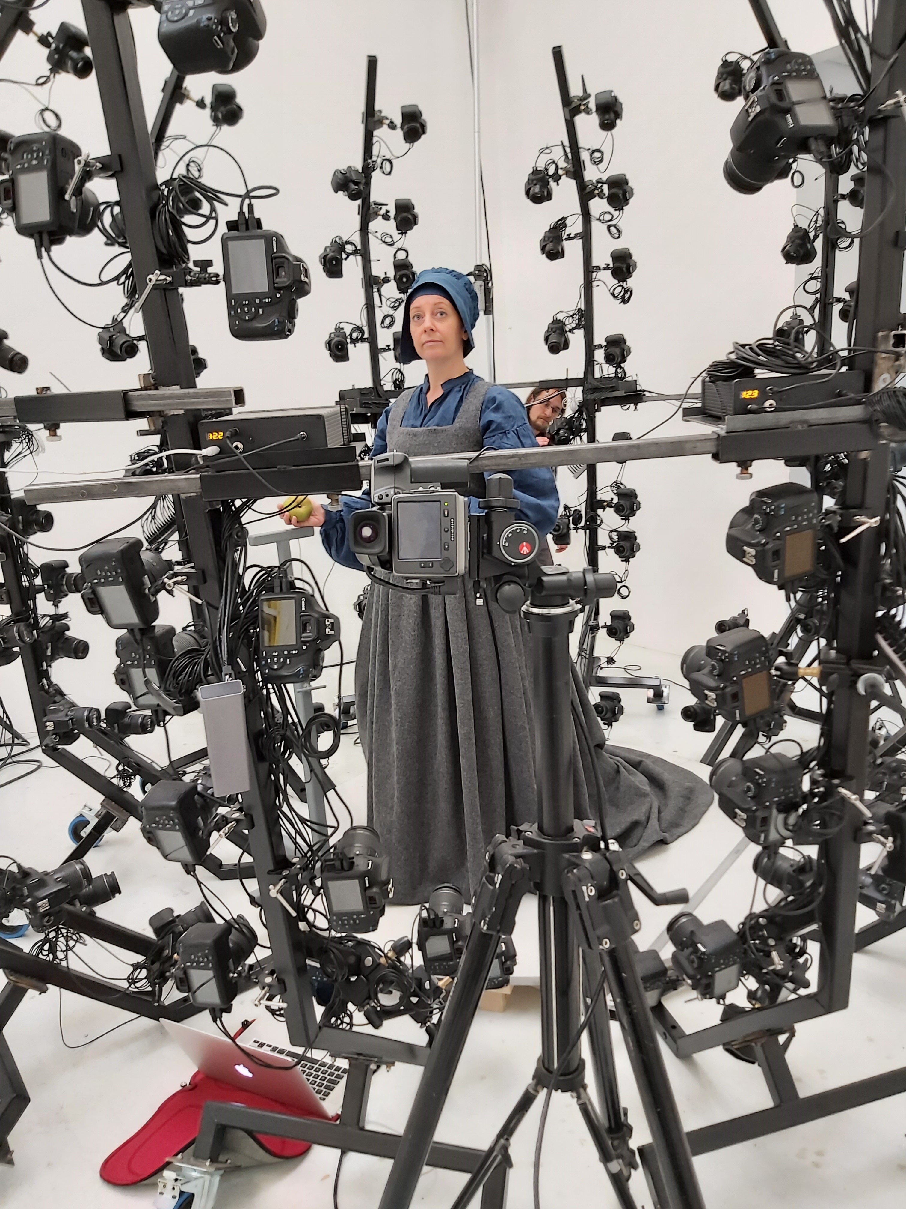 A woman stands, surround by cameras on a circular rig.