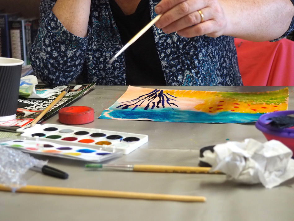 An older lady takes part in painting with water colours.