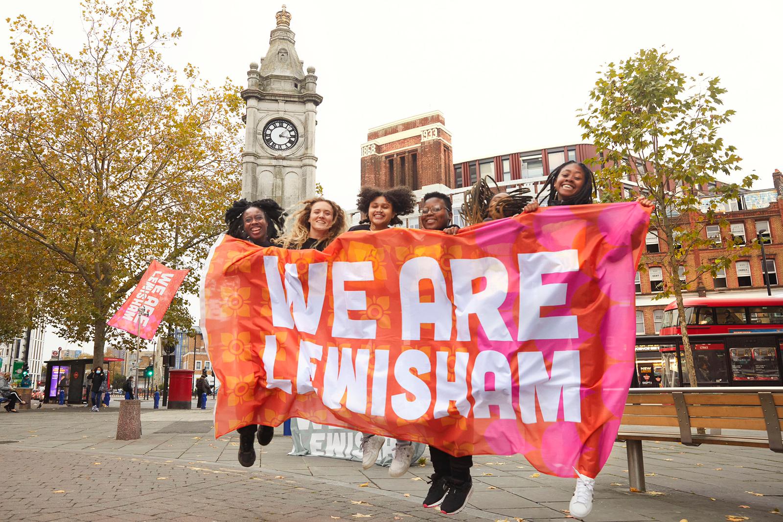 A photograph of a group of people holding a sign that reads: We Are Lewisham.
