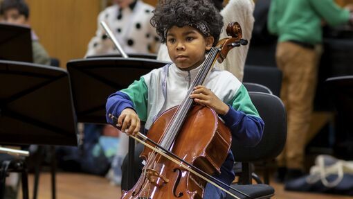 A young boy with black hair plays the cello