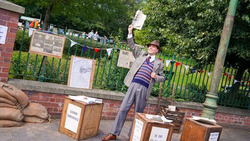 A character actor dressed in 1940s clothing sells newspapers at the Black Country Living Museum 