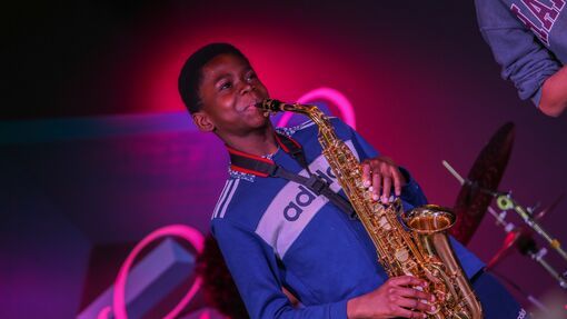 Young boy playing the saxophone on stage. 