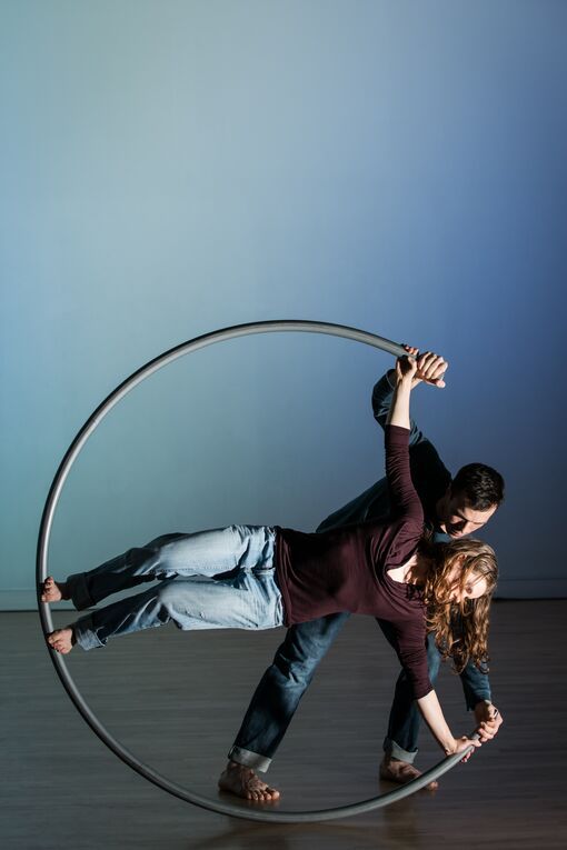 Two performers hold a pose in the Cyr wheel 